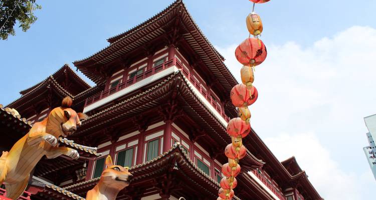 Traditional Chinese temple with red wooden beams and hanging lanterns framed by giant tiger statues