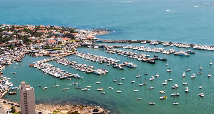 Aerial view of Punta del Este marina packed with yachts and sailboats surrounded by turquoise sea.