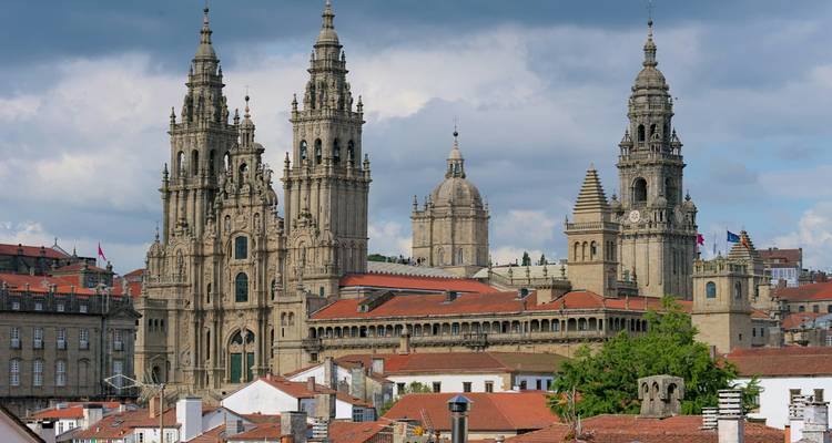 Panoramic view of Santiago de Compostela Cathedral complex above red-tiled rooftops