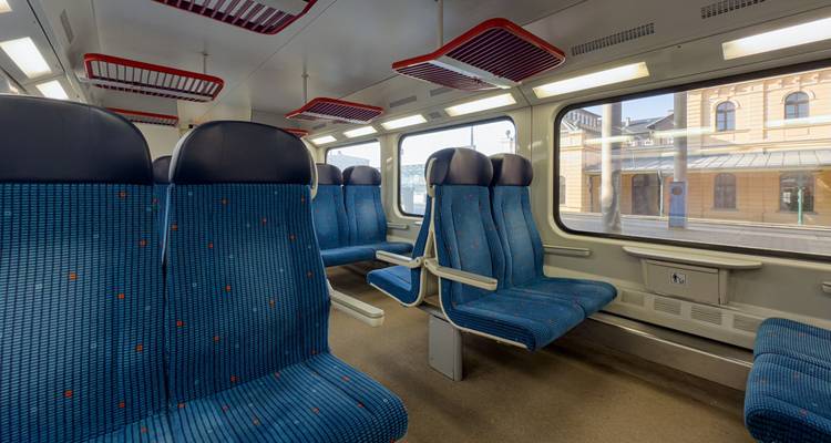 Intérieur vide d'une voiture de train régional moderne avec des sièges à motifs bleus et de grandes fenêtres.