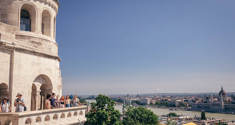 Besucher stehen auf der Terrasse der Fischerbastei und blicken auf die Donau und das Ungarische Parlament in Budapest.