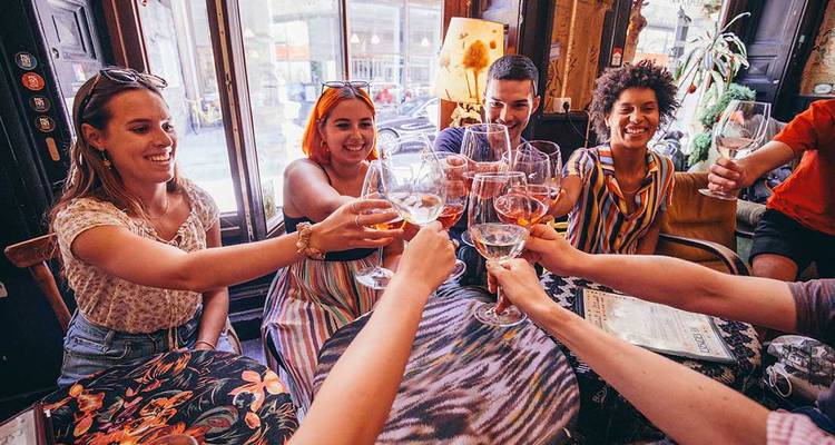 Groupe d'amis levant leurs verres dans un bar vintage confortable, célébrant ensemble.