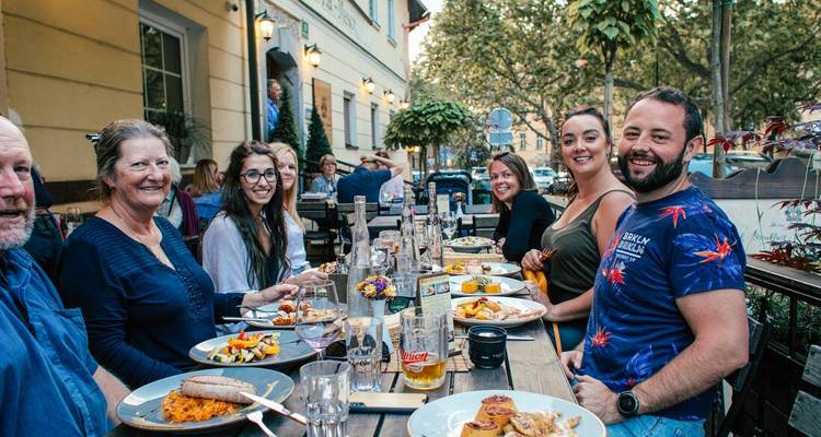 Groupe de voyageurs partageant un dîner dans un restaurant en plein air à l'ombre des arbres.