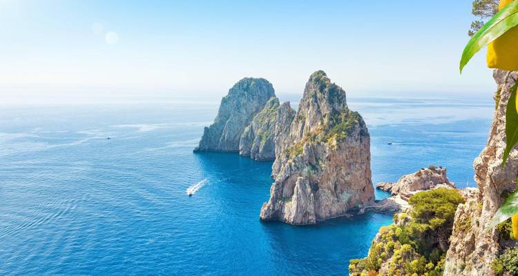 Iconic Faraglioni rock stacks rising from the turquoise waters off Capri’s rugged coast under clear skies.