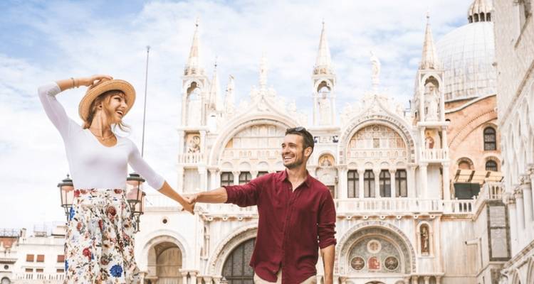 Joyful couple holding hands in front of the ornate façade of St. Mark’s Basilica in Venice