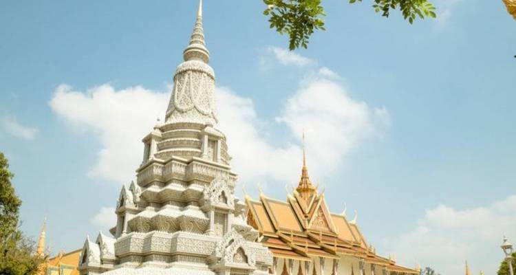 Une stupa blanche scintillante et un hall adjacent aux toits dorés s'élèvent contre un ciel tropical bleu pâle.