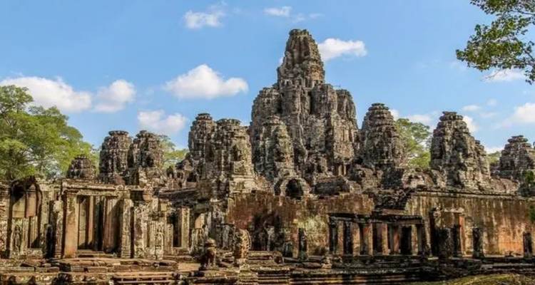 Les visages de pierre imposants du temple Bayon s'élèvent au-dessus des ruines de la jungle sous un ciel cambodgien d'un bleu éclatant.