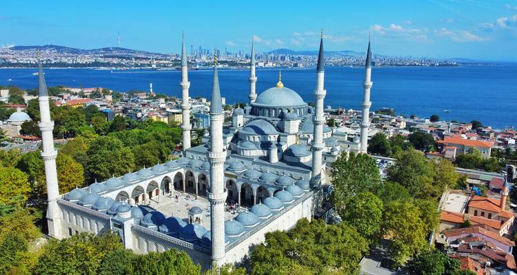 Drohnenaufnahme der Blauen Moschee, umgeben von Minaretten, mit dem Marmarameer und der Skyline der Stadt im Hintergrund.
