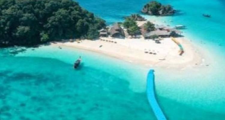 Vue aérienne floue d'une petite île avec une jetée flottante s'étendant dans une eau bleu clair