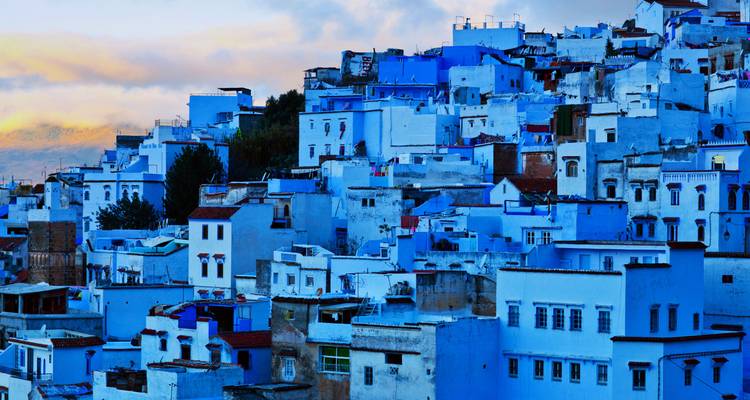 Les maisons bleues et blanches regroupées de Chefchaouen qui s'étalent en cascade sur la colline au crépuscule.