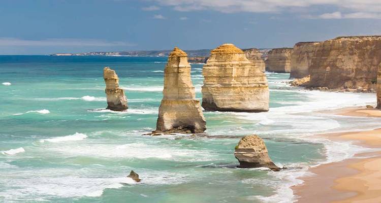 The famous limestone stacks of the Twelve Apostles rise from turquoise waves along a dramatic coastline.