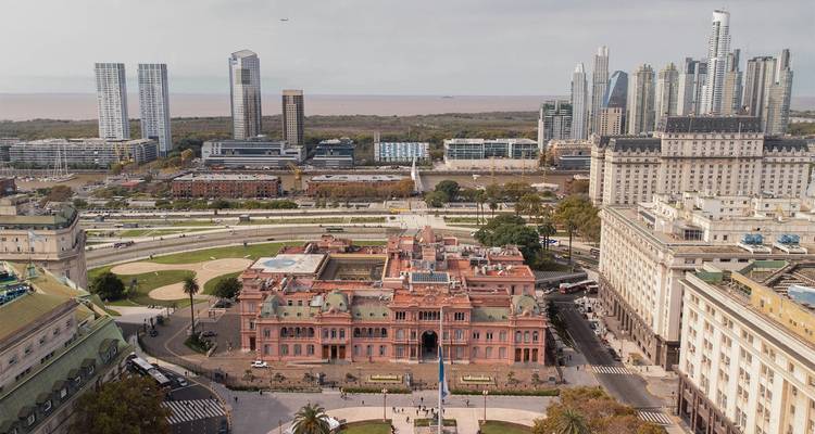 Aerial view of Buenos Aires with the pink Casa Rosada in the foreground and modern high-rises behind.