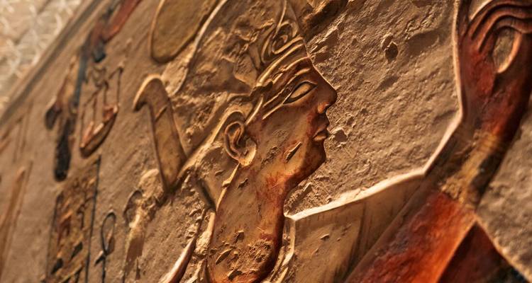 Close-up of intricate hieroglyphic relief depicting an Egyptian profile figure on a sandstone wall.