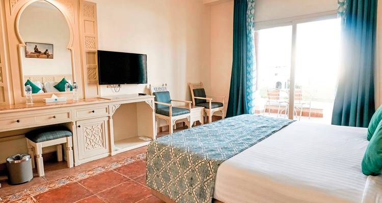 Hotelzimmer im Küstenresort-Stil mit türkisfarbener Einrichtung, Balkontüren und Fliesenböden