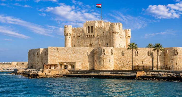 Medieval seaside Citadel of Qaitbay in Alexandria glows in warm sunlight above turquoise waters.
