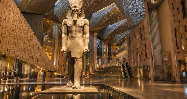 Colossal Ramesses II statue stands under the glass-roofed hall of the Grand Egyptian Museum.
