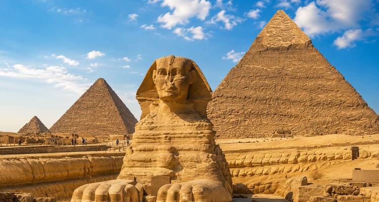 Iconic Sphinx framed by the Great Pyramids rising from the Giza Plateau under bright skies.