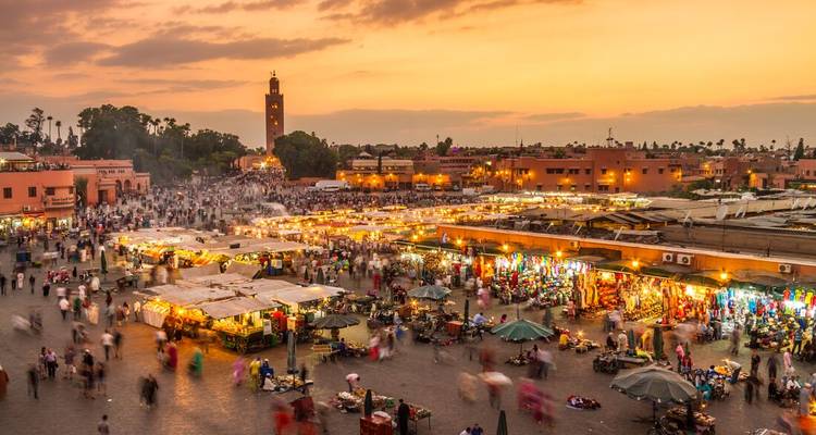 La place animée de la Jemaa el-Fna illuminée par des centaines d'étalages et de lumières alors que le soleil se couche sur Marrakech.
