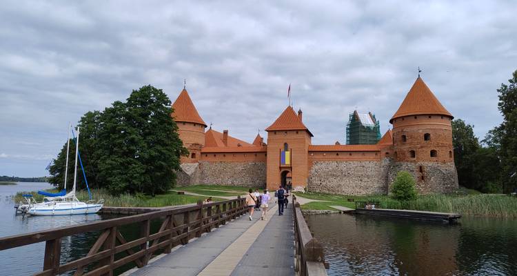 Iconic island castle with red towers reached by a wooden footbridge over a reflective lake.