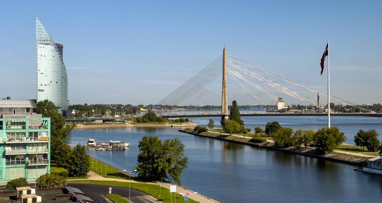 Vue panoramique sur le fleuve Daugava mettant en vedette un pont à haubans, des immeubles de grande hauteur modernes et le drapeau letton.