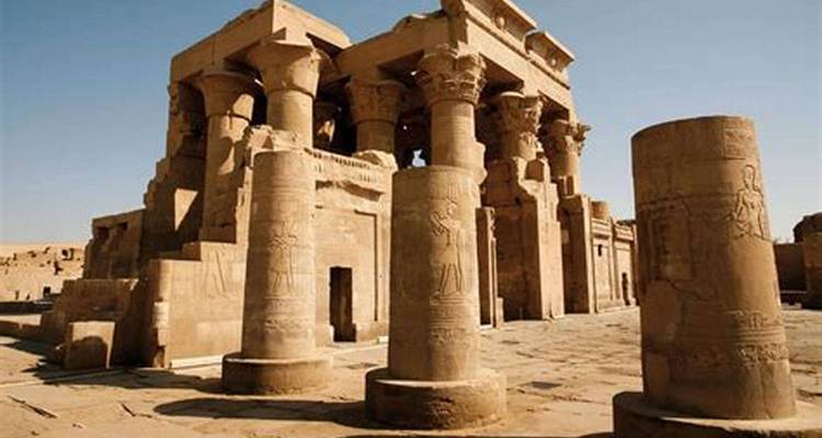 A sunlit view of Kom Ombo Temple’s thick stone pillars and relief carvings against a clear sky.
