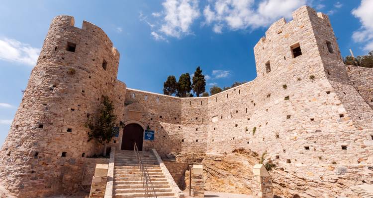 Stone walls and towers of Kusadasi's Pigeon Island Castle under a bright blue sky.