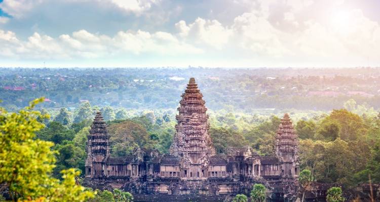 Vista panorámica de Angkor Wat elevándose sobre la densa jungla con un cielo nublado y dramático