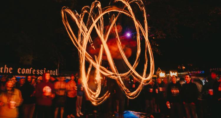 Artista de fuego en un evento nocturno al aire libre con audiencia.