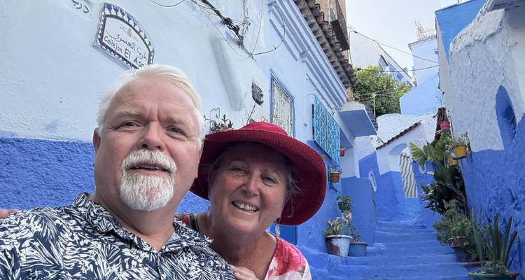 Un couple souriant prend un selfie dans une ruelle bleue étroite de Chefchaouen