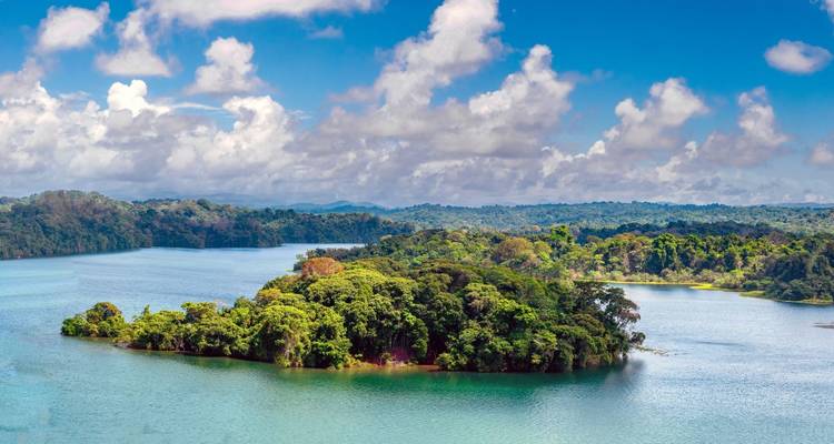 Isla exuberante y verde rodeada de aguas tranquilas y azules del lago bajo un cielo nublado y brillante en Panamá.