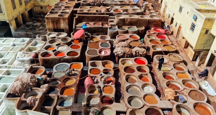 An aerial view of Fes leather tanneries shows multicoloured dye vats and workers at their craft.