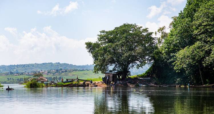Rural riverside scene with villagers, fishing boats and lush green hills.