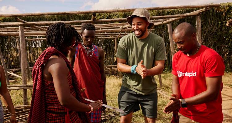 Les voyageurs et les hôtes Maasai applaudissent et sourient ensemble lors d'un échange culturel diurne.