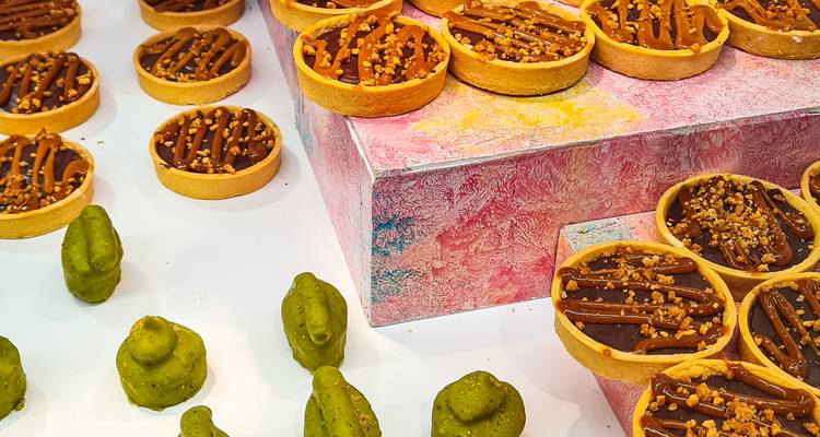 Assortiment de pâtisseries artisanales et de confiseries vertes en pâte d'amande exposés sur un présentoir coloré