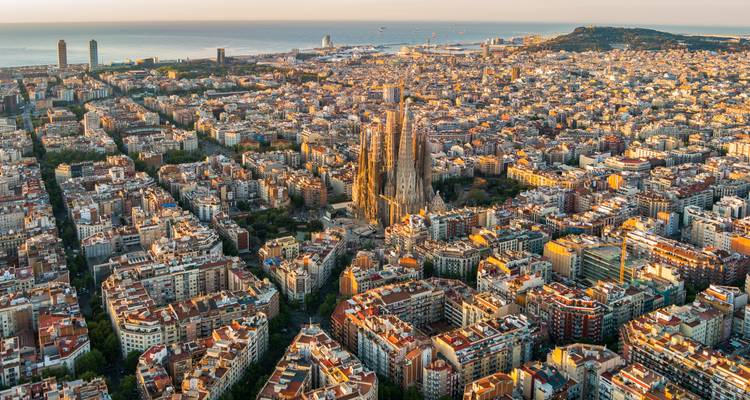 Vue aérienne du lever de soleil à Barcelone avec la Sagrada Familia dominant au milieu d'une grille de rues et la mer au-delà