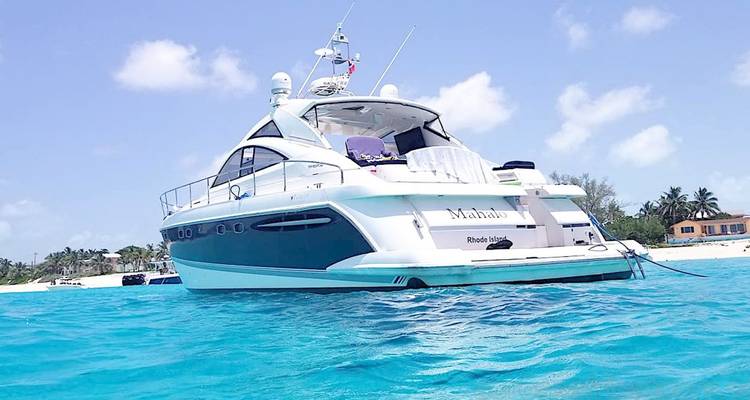 Sleek white motor yacht anchored on brilliant turquoise water near a sandy shore