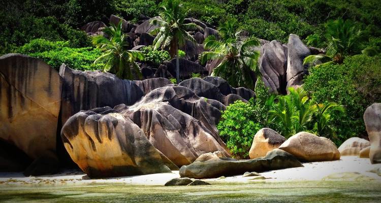 Dramatic granite boulders and lush palms fringe a pristine white-sand beach