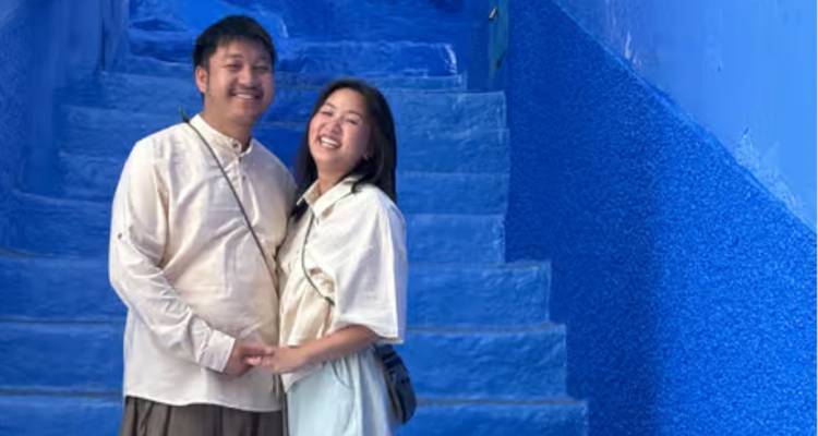 Smiling couple holding hands on bright blue stairs of Chefchaouen