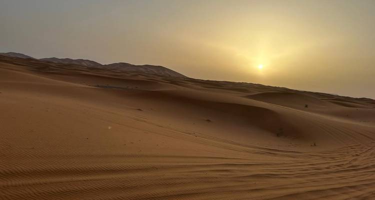 Vue sereine du soleil se couchant sur les dunes de sable ondulantes laissant une lumière douce sur le désert