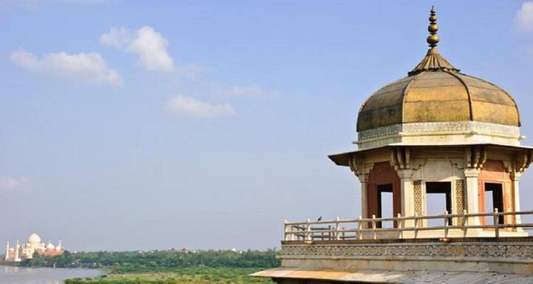 Un pavillon moghol au Fort d'Agra surplombe la rivière Yamuna avec le Taj Mahal lointain à l'horizon.