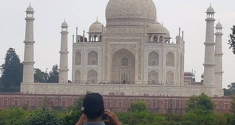 Un touriste photographie le Taj Mahal depuis l'autre rive du fleuve lors d'une journée brumeux.