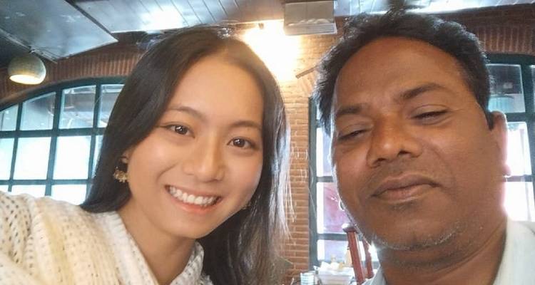 Close selfie of young woman and local guide inside a cafe with brick walls.