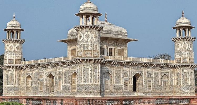Vista lateral de la tumba de Itimad-ud-Daulah con sus intrincados incrustaciones contra un cielo azul despejado.