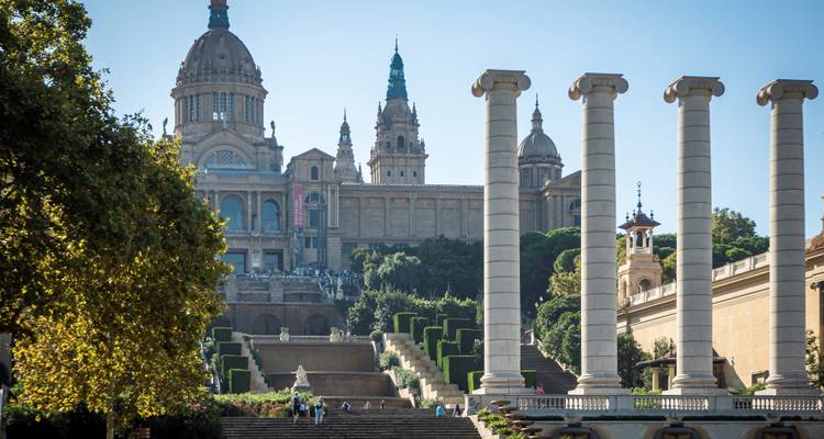 View up the grand stairway toward the Museu Nacional d’Art de Catalunya framed by four iconic columns and manicured gardens.