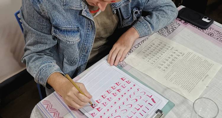 Un participante practica escritura nepalí en un cuaderno durante un taller cultural.