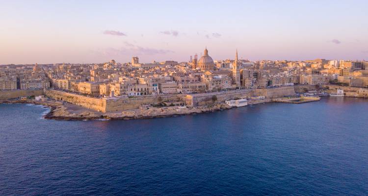 Twilight view of Valletta skyline with domes and spires seen across calm dark water
