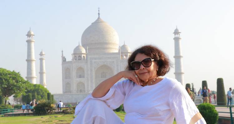 Vrouw in wit outfit die nadenkend poseert voor de Taj Mahal.