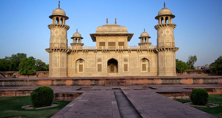 Ornate Itimad-ud-Daulah mausoleum with symmetrical towers against a deep blue evening sky.