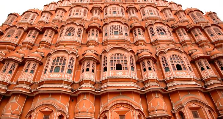 Upward view of Jaipur's pink Hawa Mahal façade with intricate windows.