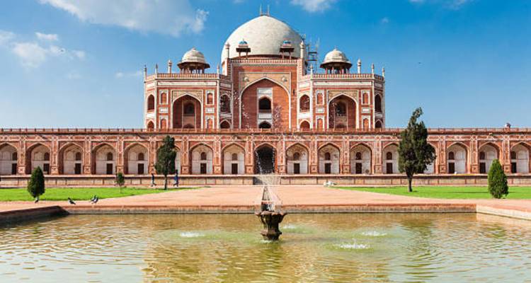 Humayun's Tomb reflected in a rectangular pool on a sunny day.